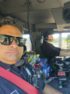Person wearing sunglasses inside a vehicle with various equipment and objects around
